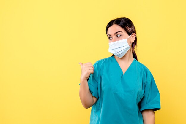 Vista lateral de un médico, una mujer en uniforme médico apunta hacia el lado