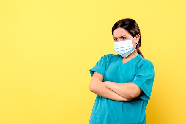 Vista lateral del médico en uniforme médico azul habla sobre la importancia de usar máscara