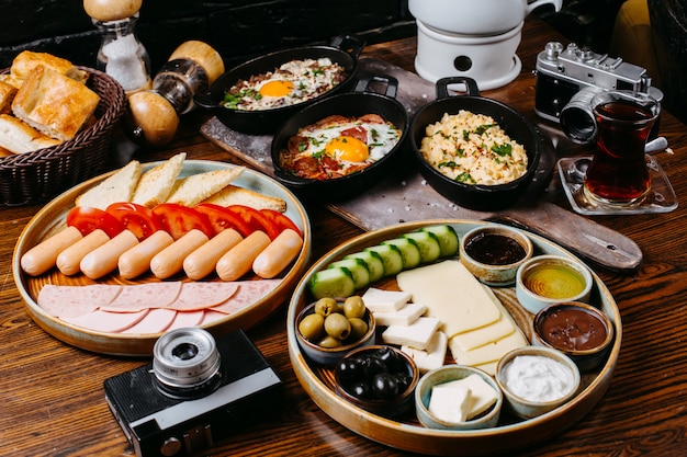 Vista lateral de la mesa de desayuno con salchichas verduras frescas queso jamón y salsas jpg