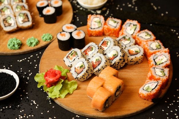 Vista lateral mezclar rollos de sushi en una bandeja con jengibre y wasabi