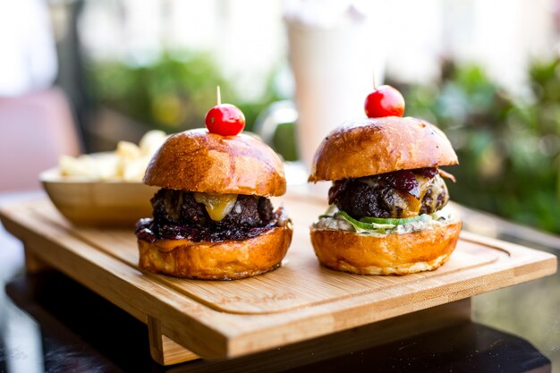 Vista lateral mini hamburguesas con queso empanizado de ternera cebolla asada pepino y tomate