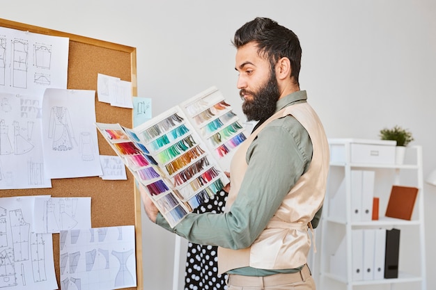 Vista lateral de la moda masculina trabajando con paleta de colores en el atelier