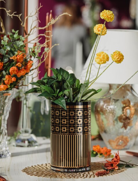 Vista lateral del moderno jarrón de vidrio con estampado geométrico con flores amarillas en una mesa de madera