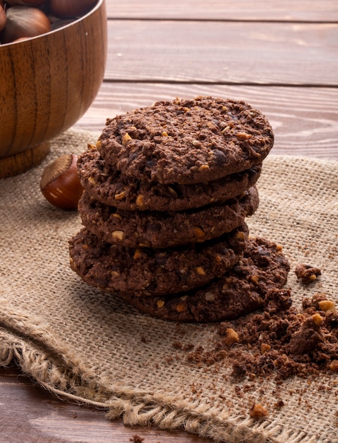 Vista lateral de un montón de galletas de chispas de chocolate con cereales, nueces y cacao en madera