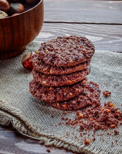 Vista lateral de un montón de galletas de chispas de chocolate con cereales, nueces y cacao en madera