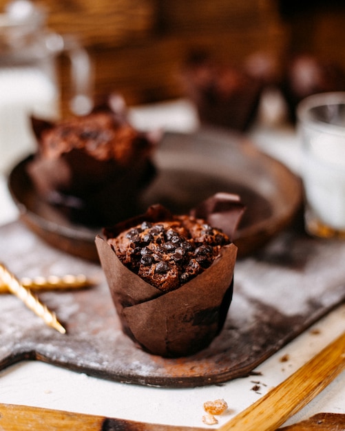 Vista lateral de muffin de chocolate sobre una tabla para cortar madera