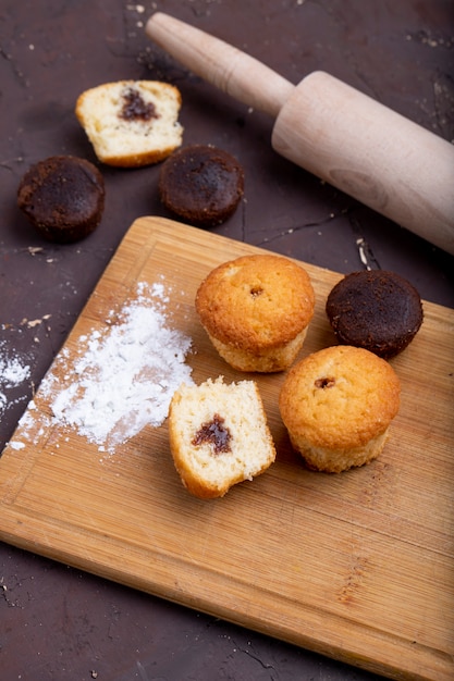 Vista lateral de muffins con chocolate sobre una tabla para cortar madera