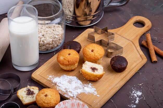 Vista lateral de muffins con chocolate sobre una tabla para cortar madera