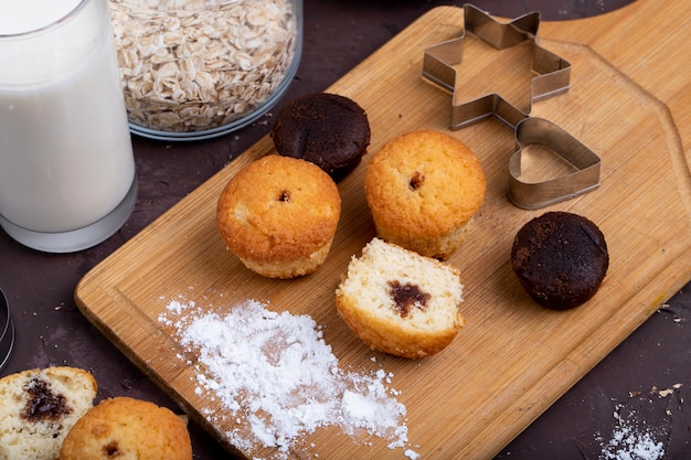 Vista lateral de muffins con chocolate sobre una tabla para cortar madera