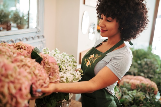 Vista lateral de una mujer afro-africana que mira el ramo de flores