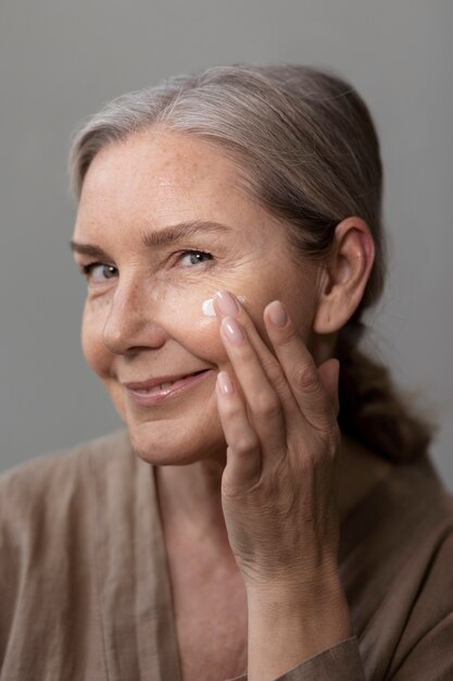Vista lateral mujer aplicando crema facial
