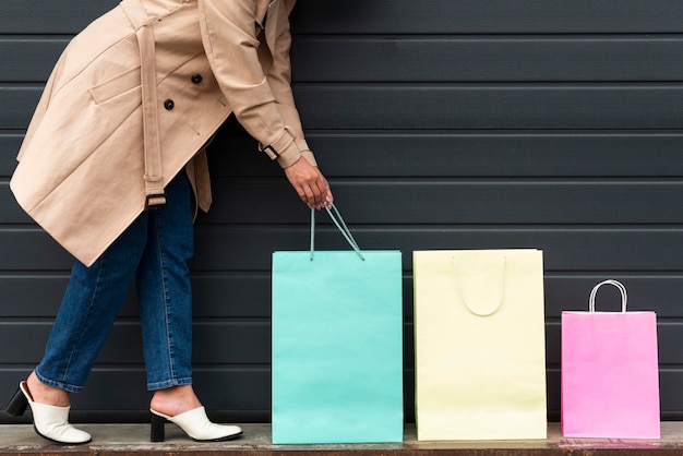 Vista lateral de la mujer arreglando bolsas de la compra de diferentes tamaños