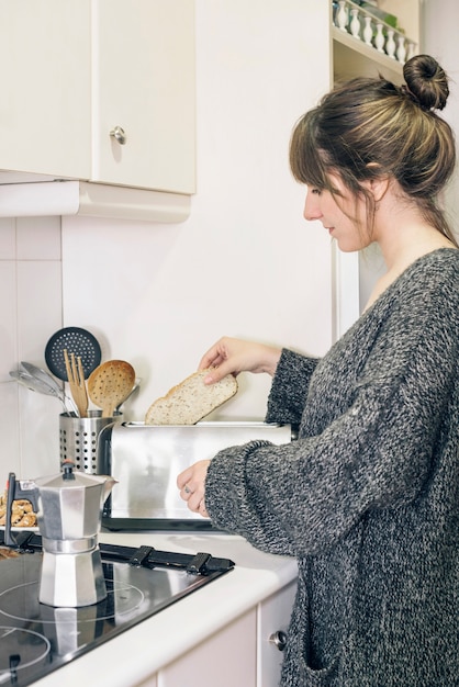 Foto gratuita vista lateral de una mujer asar pan en tostadora