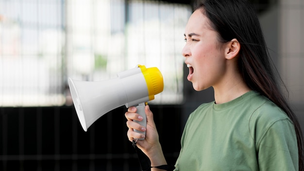 Vista lateral mujer asiática gritando en megáfono