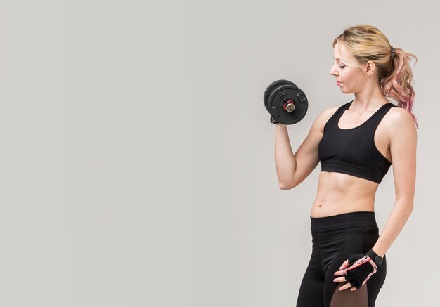 Vista lateral de la mujer en athleisure levantando peso con espacio de copia