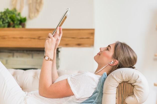 Vista lateral de la mujer con el auricular mirando la tableta digital