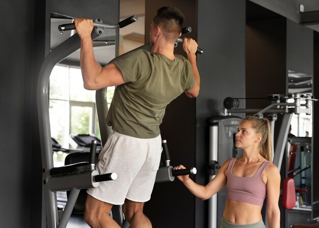 Vista lateral mujer ayudando al hombre en el gimnasio