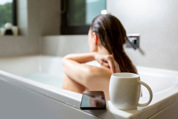 Foto gratuita vista lateral mujer en bañera con taza de café