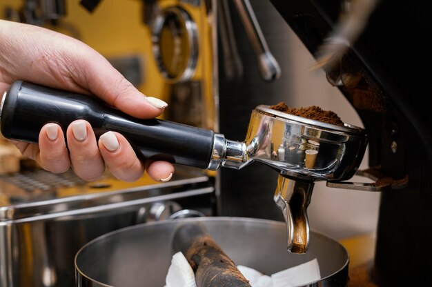 Vista lateral de la mujer barista con máquina de café profesional
