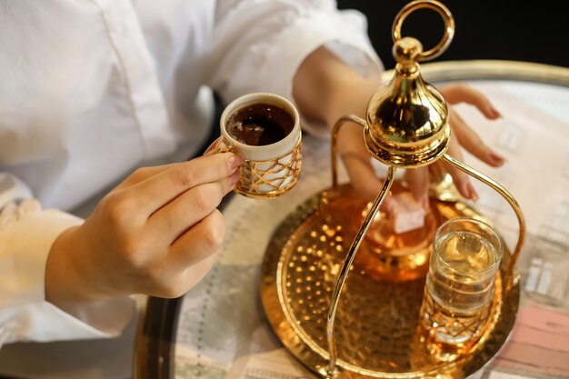 Vista lateral mujer bebiendo café turco con delicias turcas y un vaso de agua