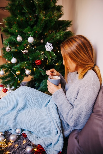 Foto gratuita vista lateral de mujer bebiendo té al lado de árbol de navidad