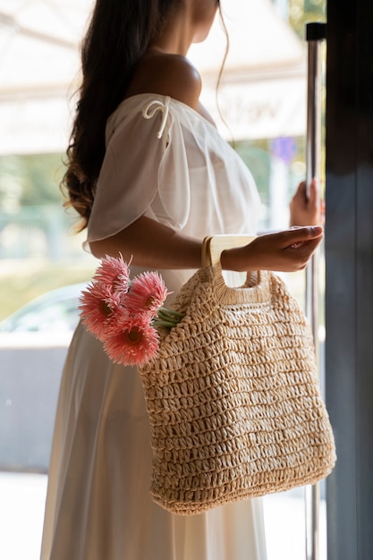 Vista lateral mujer bolsa de transporte con flores.