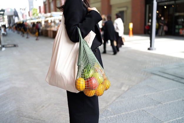 Foto gratuita vista lateral mujer bolsa de transporte con frutas