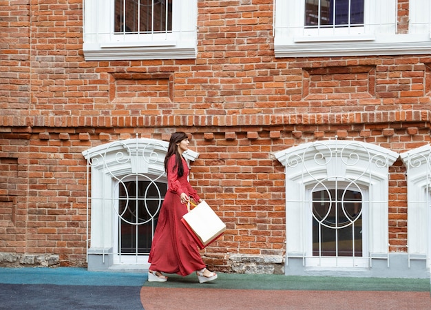 Vista lateral de la mujer caminando con bolsas de la compra.