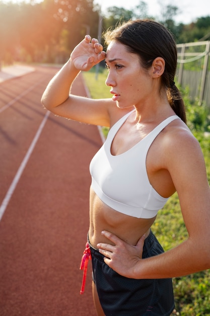 Foto gratuita vista lateral mujer cansada en pista de atletismo