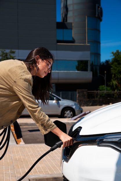 Vista lateral mujer cargando coche eléctrico