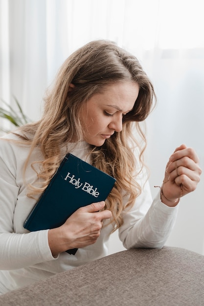 Vista lateral de la mujer en casa sosteniendo la Biblia
