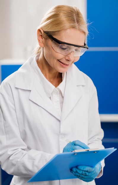 Foto gratuita vista lateral de la mujer científica con guantes quirúrgicos escribiendo algo