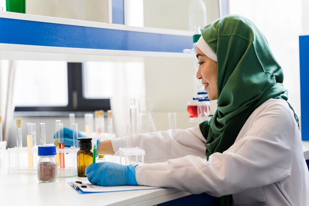 Vista lateral de la mujer científica con hijab y guantes quirúrgicos.