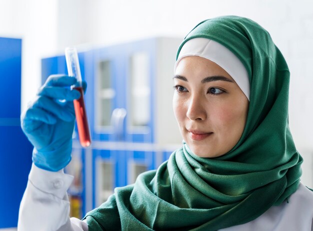 Vista lateral de la mujer científica con hijab con sustancia