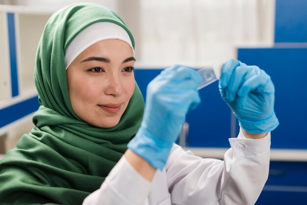 Vista lateral de la mujer científica con hijab trabajando