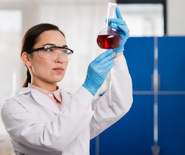Vista lateral de la mujer científico mirando sustancia de laboratorio