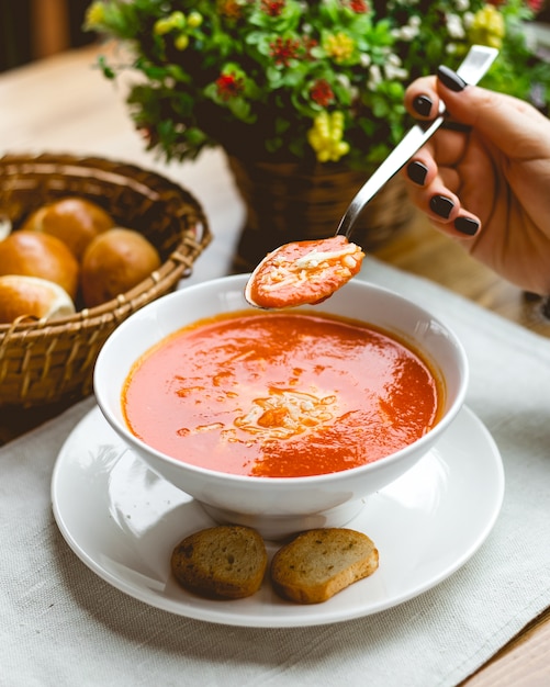 Vista lateral mujer comiendo sopa de tomate queso rallado y galletas