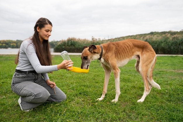 Foto gratuita vista lateral mujer dando agua al perro