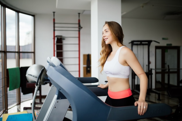 Vista lateral de la mujer deportiva haciendo ejercicio en cinta en el gimnasio