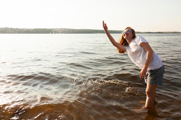 Vista lateral de la mujer divirtiéndose en el agua en el lago