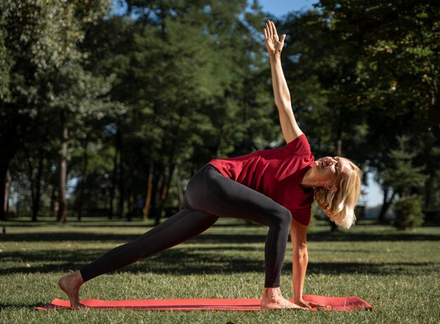 Vista lateral, de, mujer, ejercitar, posición yoga, aire libre