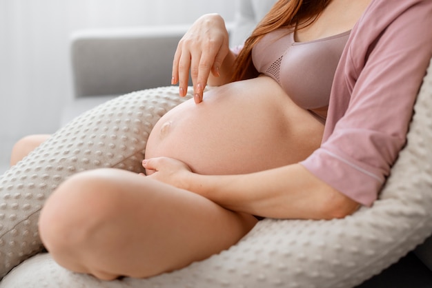 Foto gratuita vista lateral mujer embarazada en almohada de lactancia