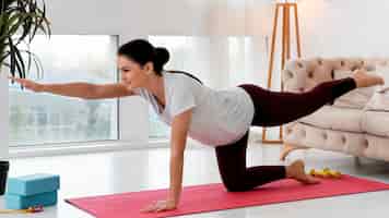 Foto gratuita vista lateral de la mujer embarazada haciendo yoga en casa