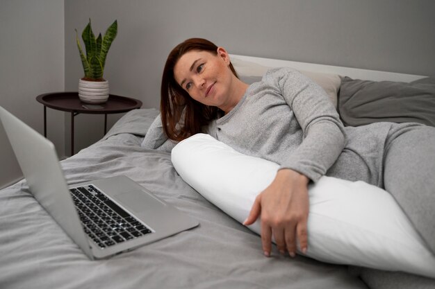 Vista lateral mujer embarazada con laptop en casa