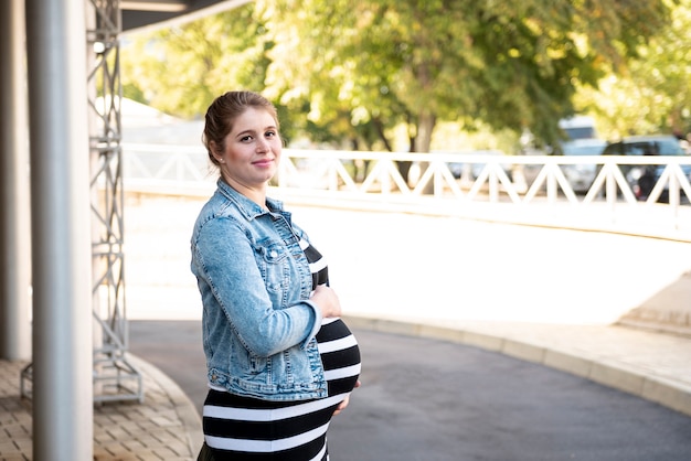 Vista lateral mujer embarazada posando al aire libre