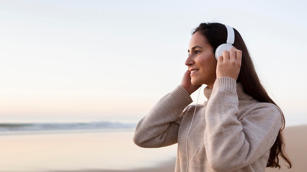Vista lateral de la mujer escuchando música con auriculares al aire libre