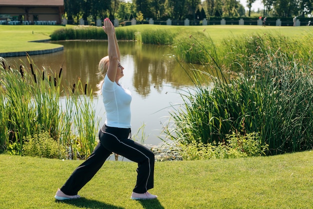 Foto gratuita vista lateral mujer estirando cerca del lago