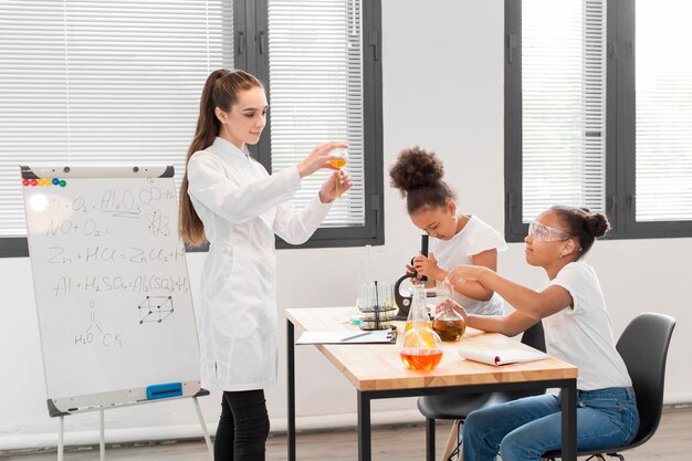 Vista lateral de la mujer explicando química a las niñas