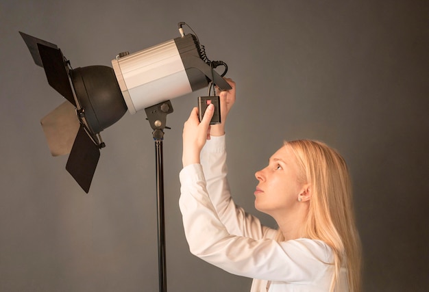 Foto gratuita vista lateral mujer fotógrafo ajustando la lámpara