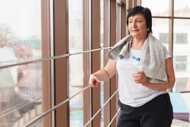 Foto gratuita vista lateral mujer en el gimnasio hidratante